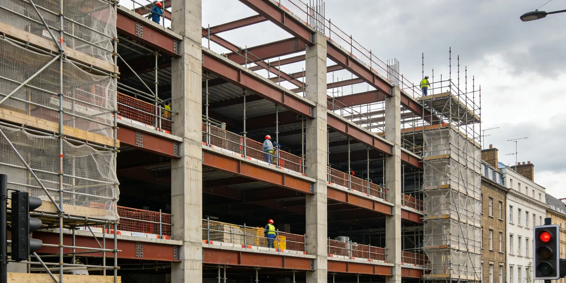 Concrete frame of a new building rising behind a Georgian terrace, with site operatives in high visibility clothing